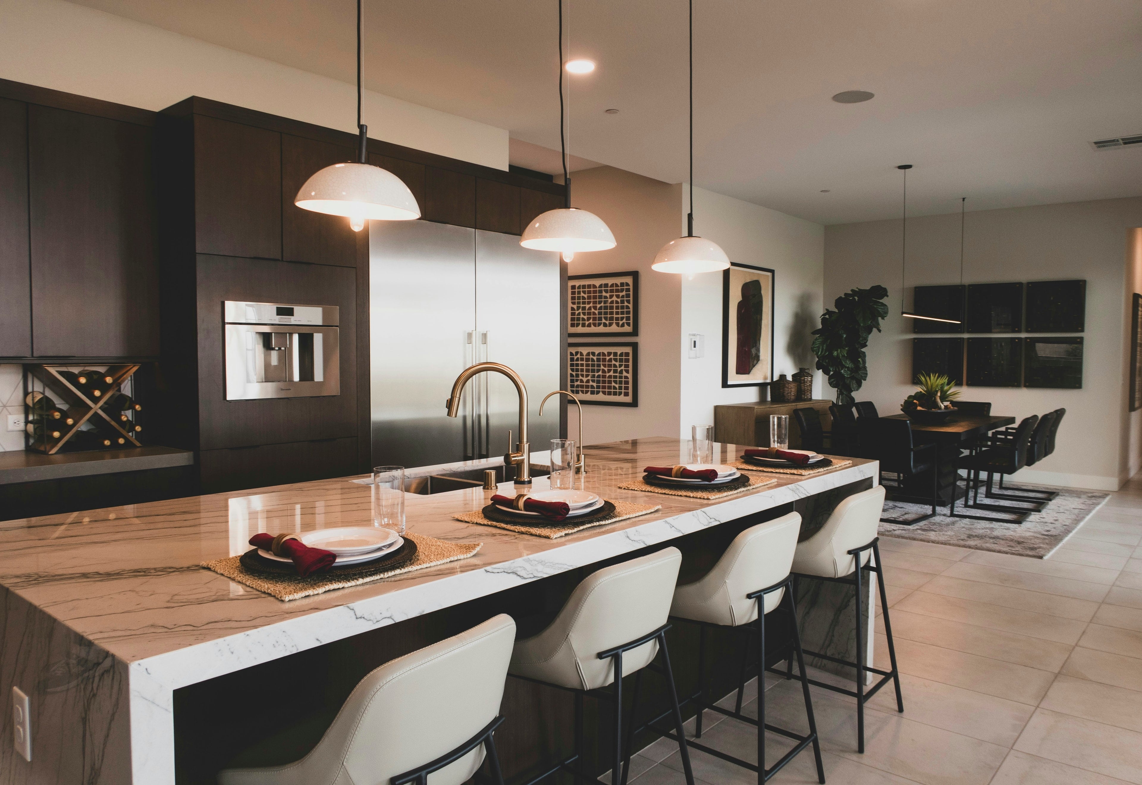 A kitchen with dark wood cabinets, a marble island and white bar stools