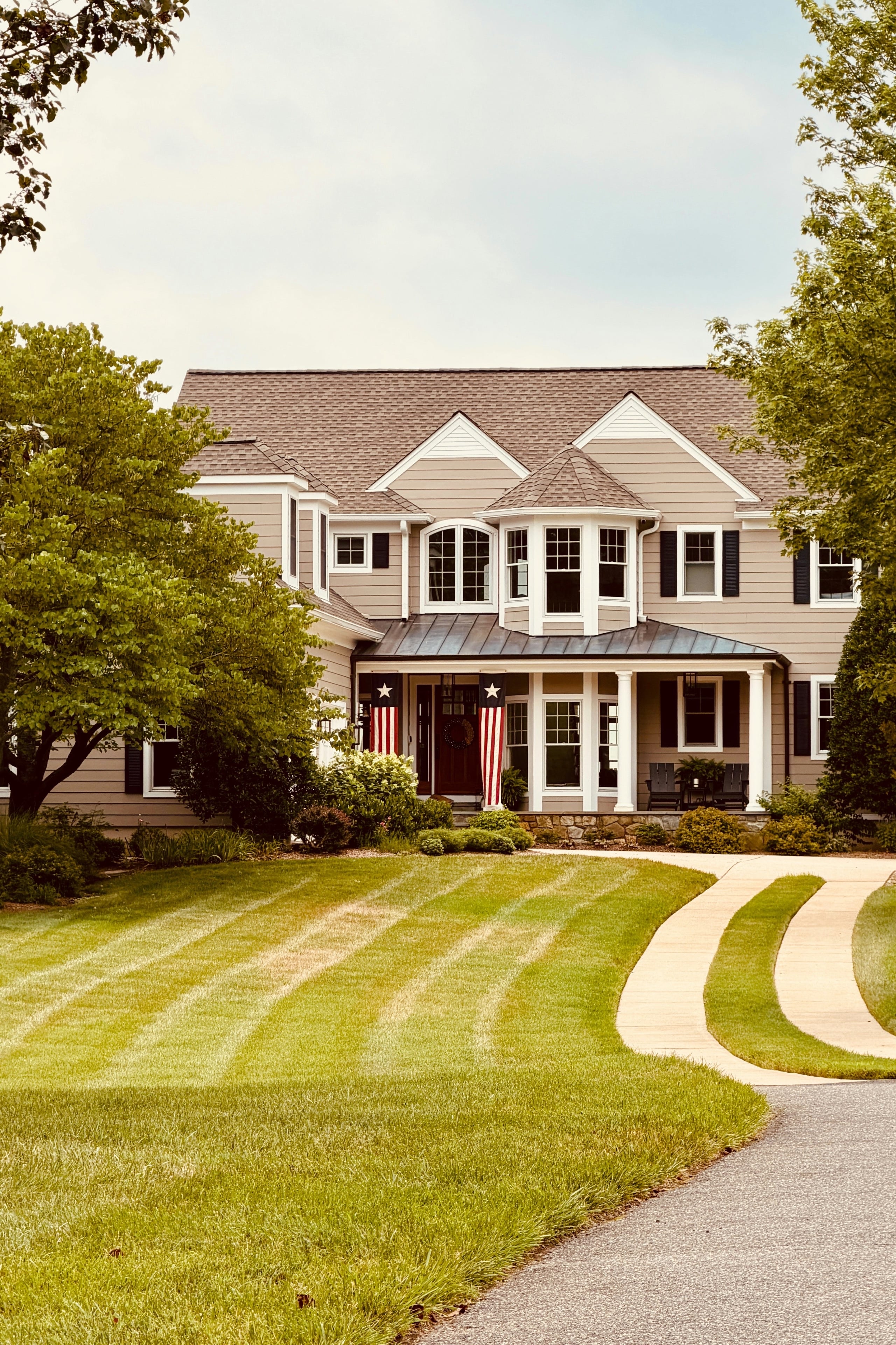 A two-story house with a covered porch and a striped lawn